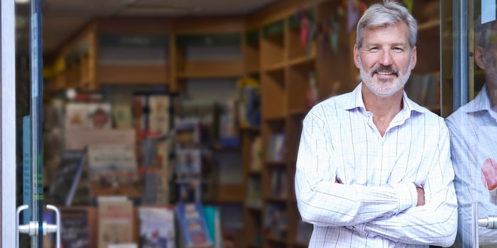 man in business casual attire crossing his arms and smiling