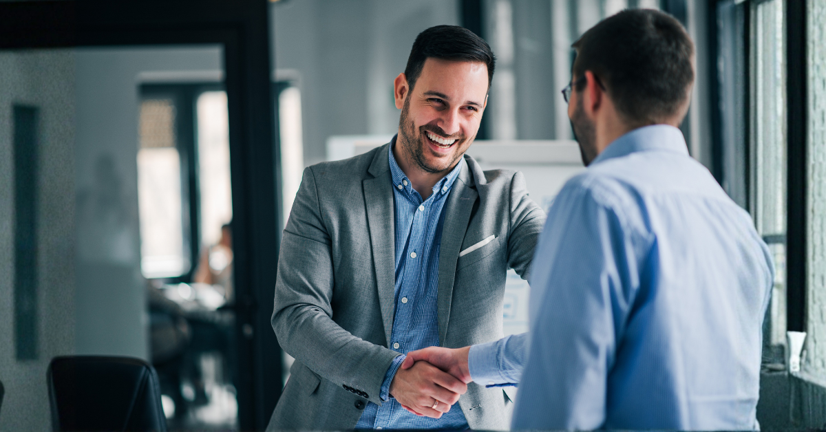 Two men shake hands in an office.