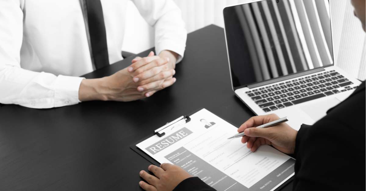 A potential employer reviews a resume during an interview with a candidate.